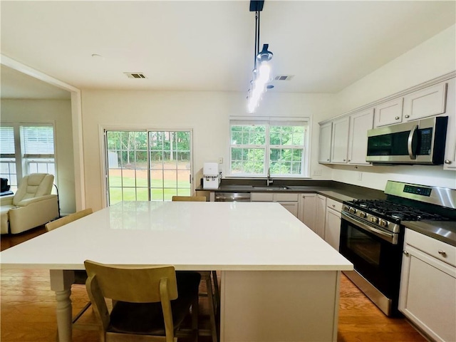 365 Friars Head Dr, Suwanee, GA 30024 - kitchen featuring appliances with stainless steel finishes, a sink, a breakfast bar, pendant lighting, and light wood-style floors
