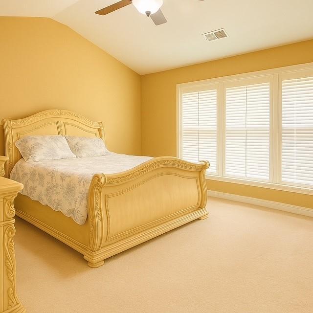 bedroom with light colored carpet, ceiling fan, visible vents, and vaulted ceiling
