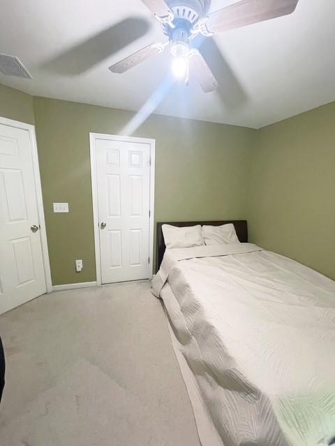 carpeted bedroom featuring visible vents, baseboards, and ceiling fan