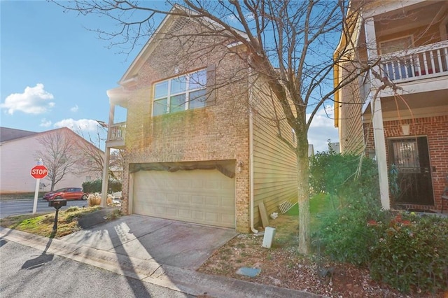 view of side of property with concrete driveway, brick siding, a balcony, and an attached garage