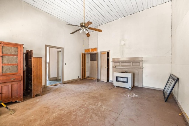 unfurnished living room featuring wooden ceiling, ceiling fan, a towering ceiling, concrete floors, and heating unit