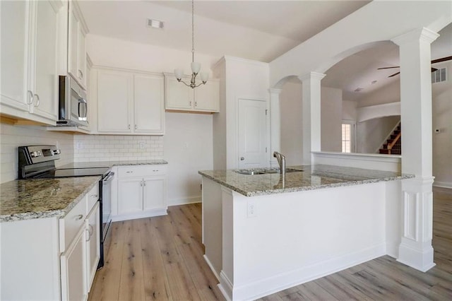 kitchen with appliances with stainless steel finishes, decorative light fixtures, white cabinetry, sink, and light stone counters