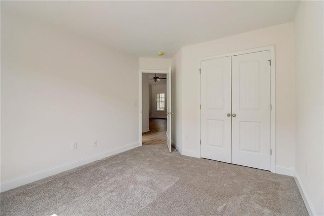 unfurnished bedroom with light colored carpet and a closet