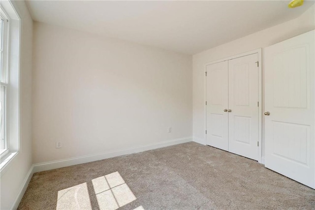 unfurnished bedroom featuring a closet and light carpet