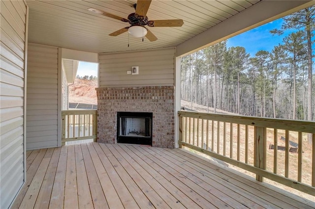 wooden terrace with an outdoor brick fireplace and ceiling fan