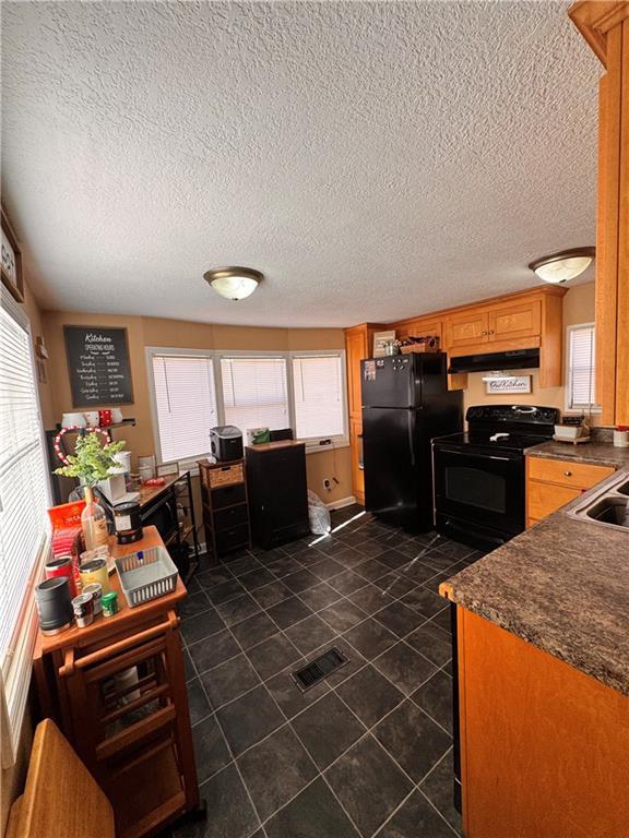 kitchen featuring a wealth of natural light, a textured ceiling, and black appliances