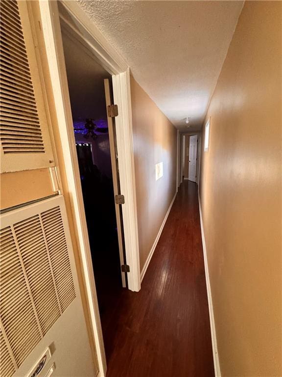 hall with a textured ceiling and dark hardwood / wood-style flooring