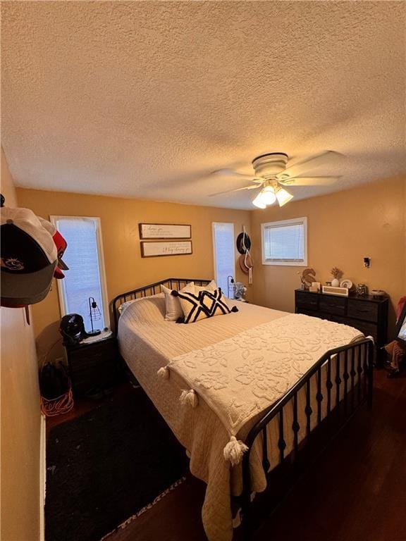 bedroom with dark wood-type flooring, ceiling fan, and a textured ceiling