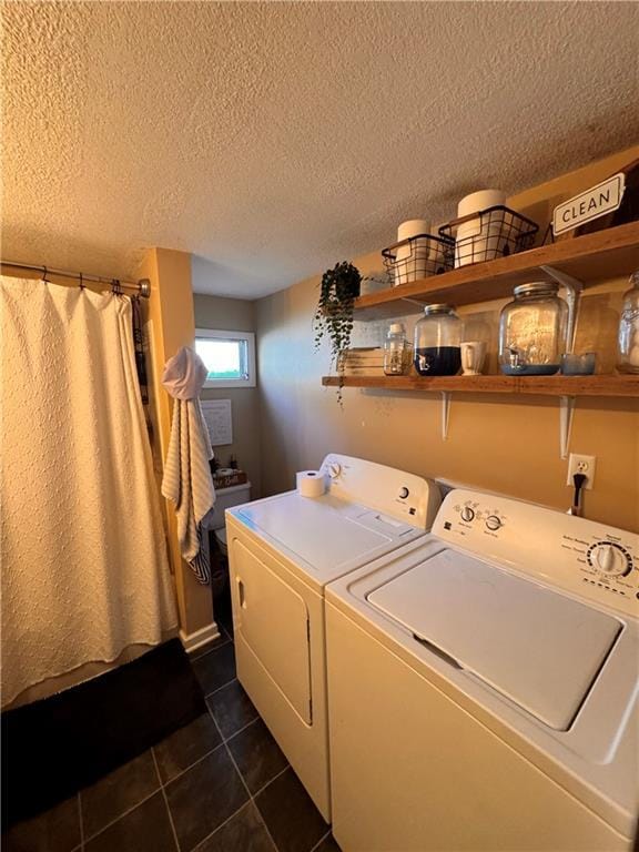 laundry area featuring washer and clothes dryer, a textured ceiling, and dark tile patterned floors