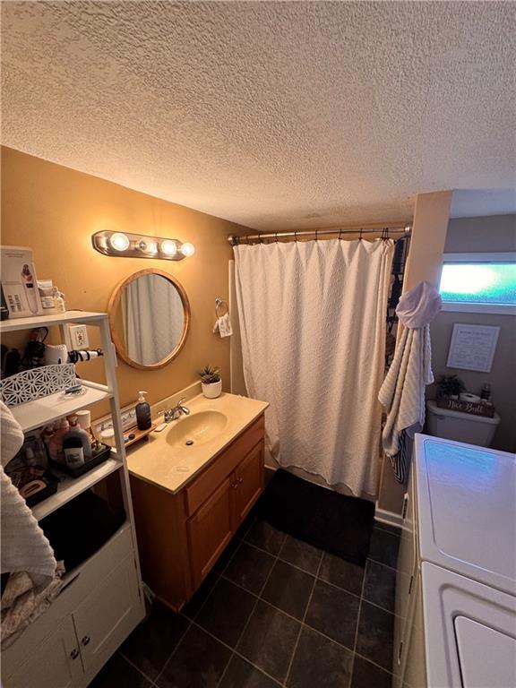 bathroom with walk in shower, vanity, and a textured ceiling