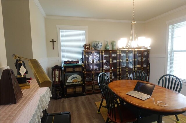 dining room with dark wood-type flooring, ornamental molding, and a chandelier