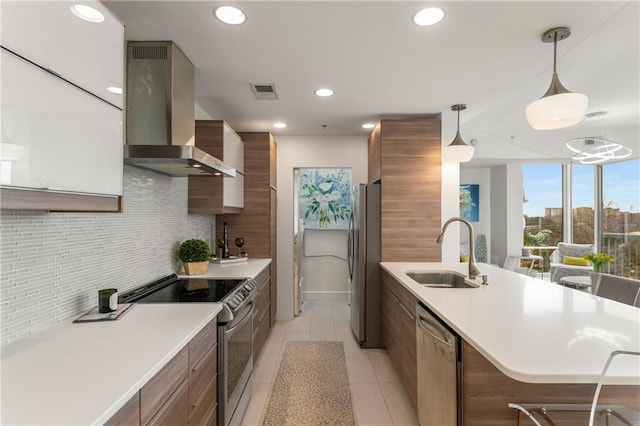 kitchen with appliances with stainless steel finishes, pendant lighting, sink, decorative backsplash, and wall chimney exhaust hood