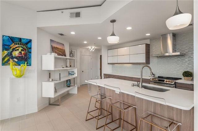 kitchen featuring wall chimney exhaust hood, a kitchen bar, sink, and white cabinets