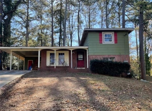 tri-level home with a carport, covered porch, driveway, and brick siding