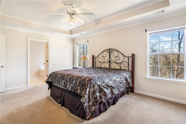 carpeted bedroom with a raised ceiling, multiple windows, ceiling fan, and ensuite bathroom