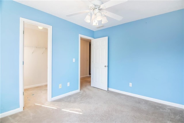 unfurnished bedroom with ceiling fan, light colored carpet, a walk in closet, and a closet