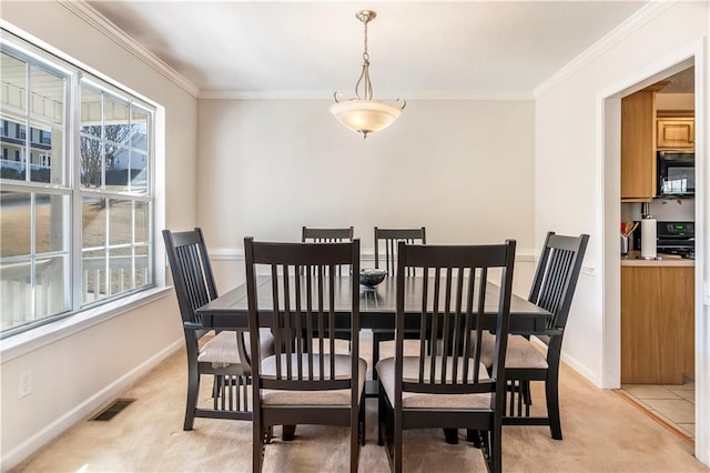 dining space featuring ornamental molding and light carpet