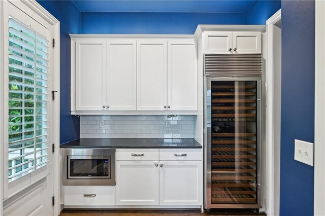 bar with stainless steel microwave, decorative backsplash, and wine cooler