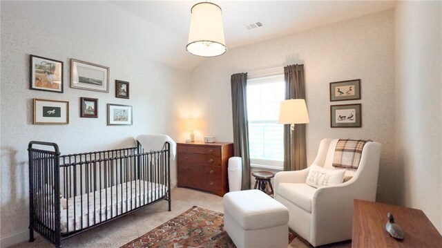 bedroom with carpet floors, a crib, vaulted ceiling, and visible vents