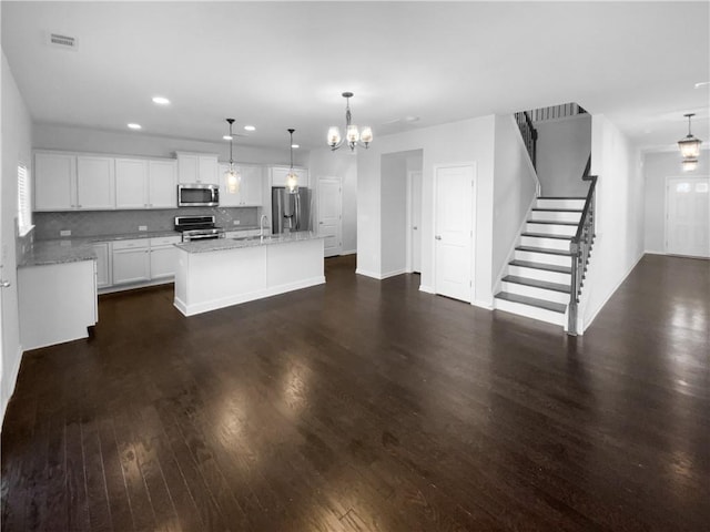 kitchen with visible vents, decorative backsplash, dark wood finished floors, stainless steel appliances, and a chandelier