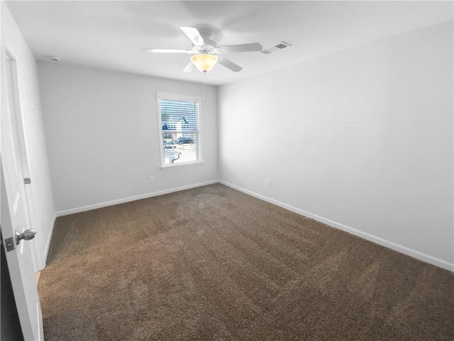 carpeted spare room featuring a ceiling fan, visible vents, and baseboards