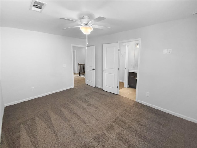 unfurnished bedroom featuring carpet, visible vents, ensuite bathroom, a ceiling fan, and baseboards