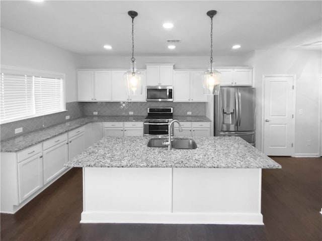 kitchen featuring visible vents, dark wood-type flooring, a kitchen island with sink, stainless steel appliances, and a sink