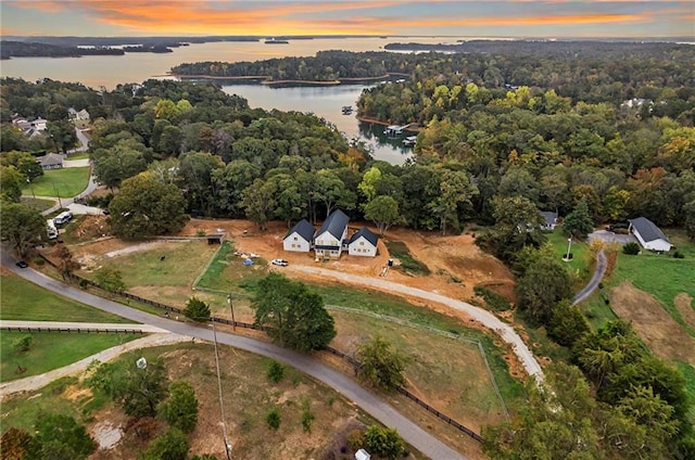 aerial view at dusk with a water view and a forest view