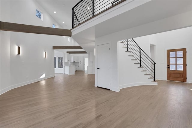 unfurnished living room with a towering ceiling and light hardwood / wood-style floors