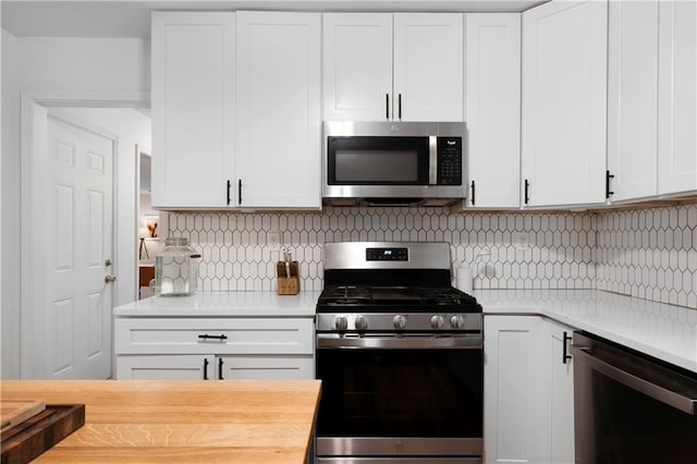 kitchen featuring butcher block countertops, decorative backsplash, appliances with stainless steel finishes, and white cabinetry