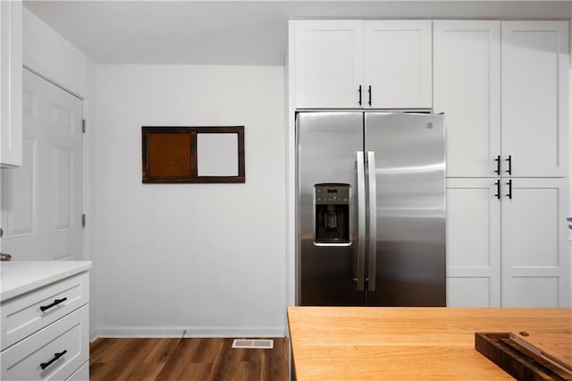 kitchen featuring stainless steel fridge with ice dispenser, dark wood-type flooring, butcher block counters, and white cabinets