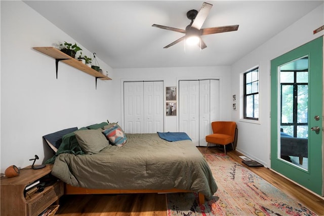 bedroom with ceiling fan, multiple closets, and hardwood / wood-style floors