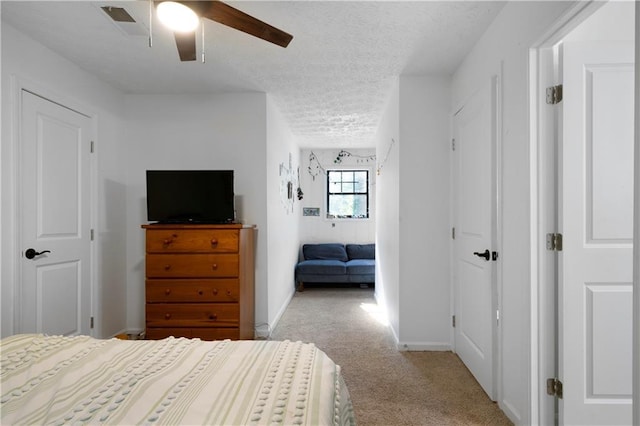 carpeted bedroom featuring ceiling fan and a textured ceiling