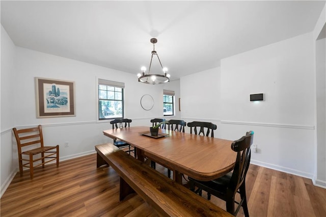 dining space featuring wood-type flooring and an inviting chandelier