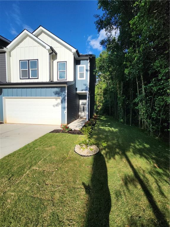 view of front of home with an attached garage, board and batten siding, a front lawn, and concrete driveway