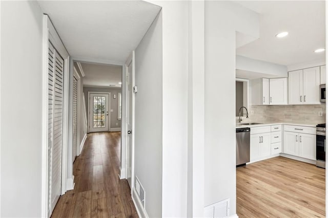 corridor with sink and light hardwood / wood-style flooring