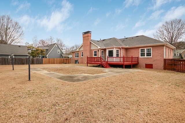 back of property featuring fence private yard, brick siding, a shingled roof, a wooden deck, and a chimney