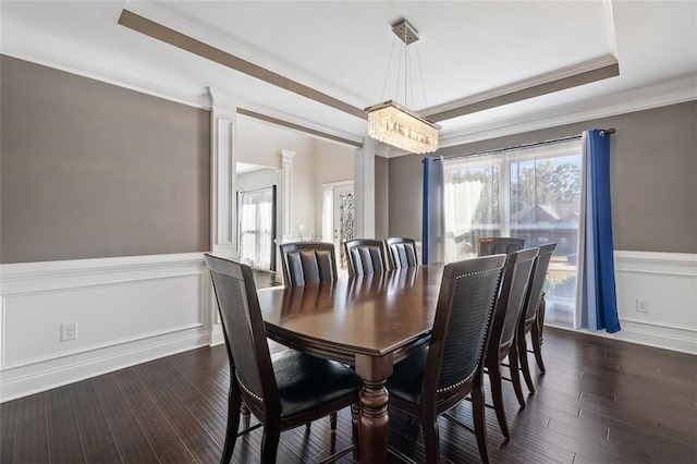 dining room with a raised ceiling, crown molding, dark hardwood / wood-style floors, and an inviting chandelier