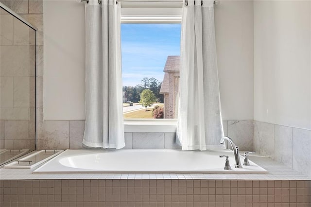 bathroom with a healthy amount of sunlight and tiled bath