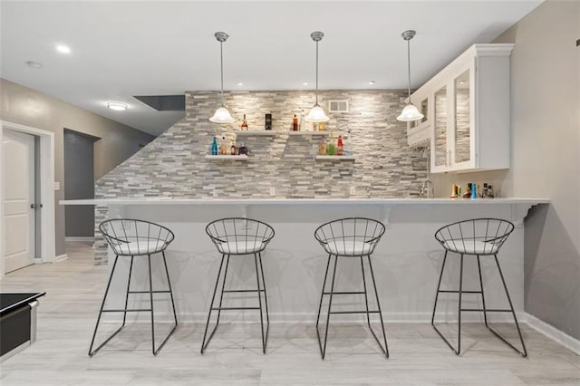 bar with light hardwood / wood-style flooring, white cabinets, and pendant lighting