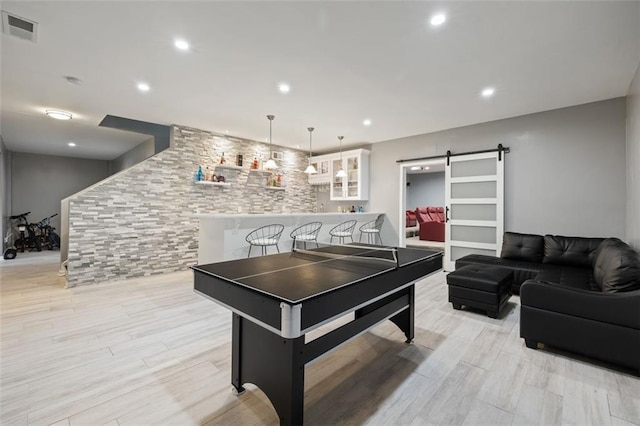 rec room featuring light wood-type flooring and a barn door