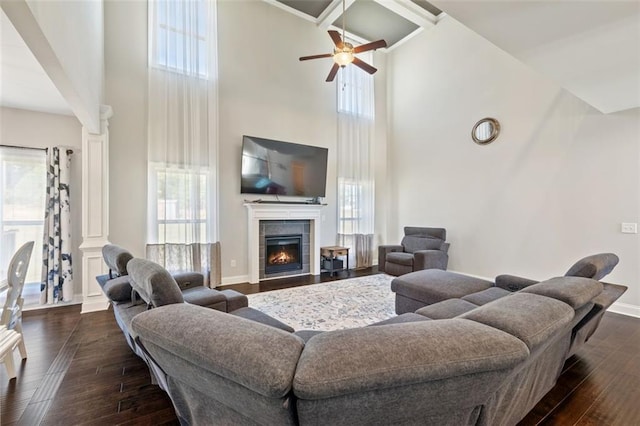 living room featuring a healthy amount of sunlight, a towering ceiling, and dark wood-type flooring