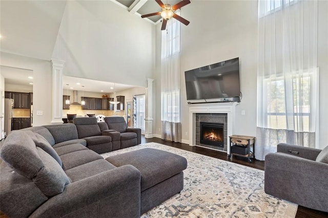 living room with plenty of natural light, a towering ceiling, and dark wood-type flooring