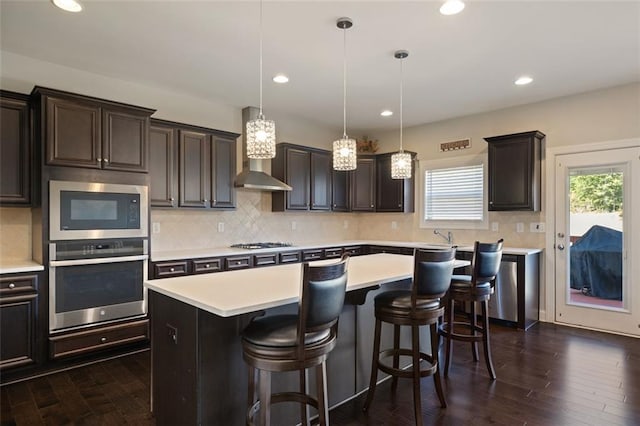 kitchen with stainless steel appliances, dark hardwood / wood-style flooring, pendant lighting, a kitchen bar, and a kitchen island