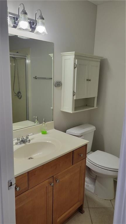 full bath featuring a shower with shower door, vanity, toilet, and tile patterned floors