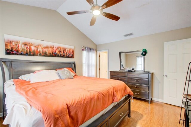 bedroom with light hardwood / wood-style floors, ceiling fan, multiple windows, and lofted ceiling