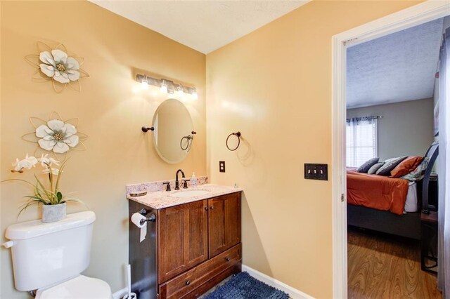 bathroom featuring hardwood / wood-style flooring, vanity, toilet, and a textured ceiling