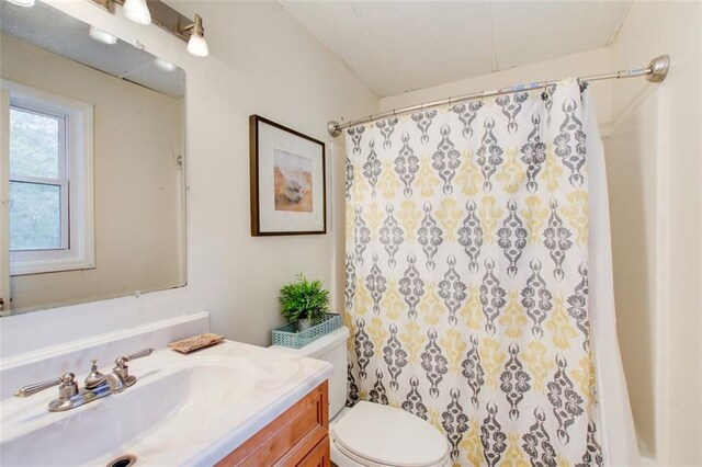 bathroom with walk in shower, vanity, and toilet