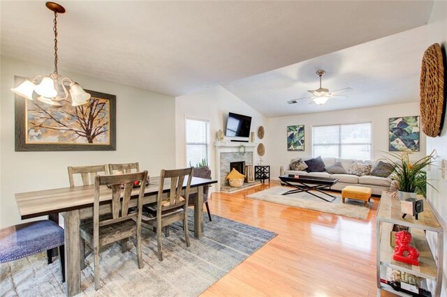 dining area featuring ceiling fan with notable chandelier, lofted ceiling, and hardwood / wood-style flooring