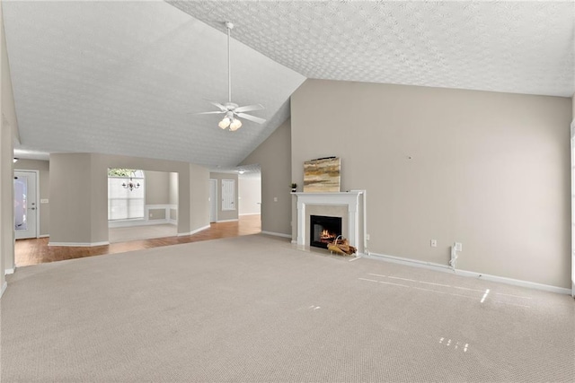 unfurnished living room featuring high vaulted ceiling, ceiling fan with notable chandelier, light colored carpet, and a textured ceiling